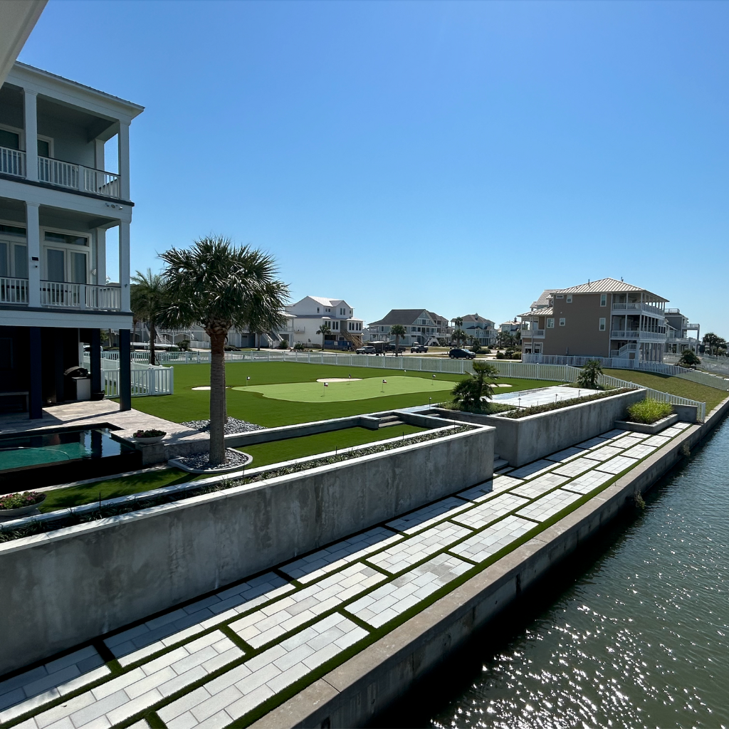 Luxury waterfront property on Galveston Bay with a custom putting green, paver work along the water, and a swimming pool.