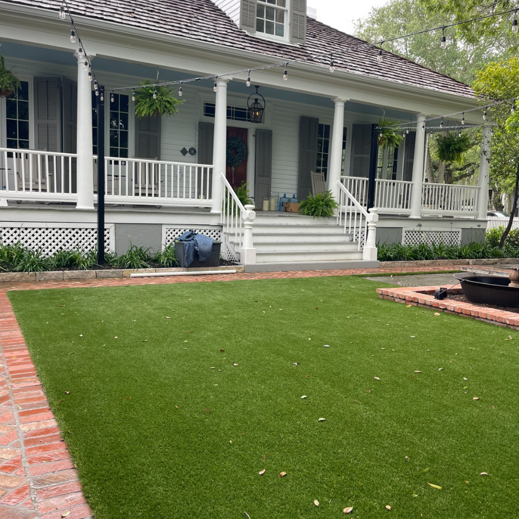 In South Houston, a front porch with a brick pathway and a luxury artificial turf lawn installation, completed by Sermons Turf Installs.