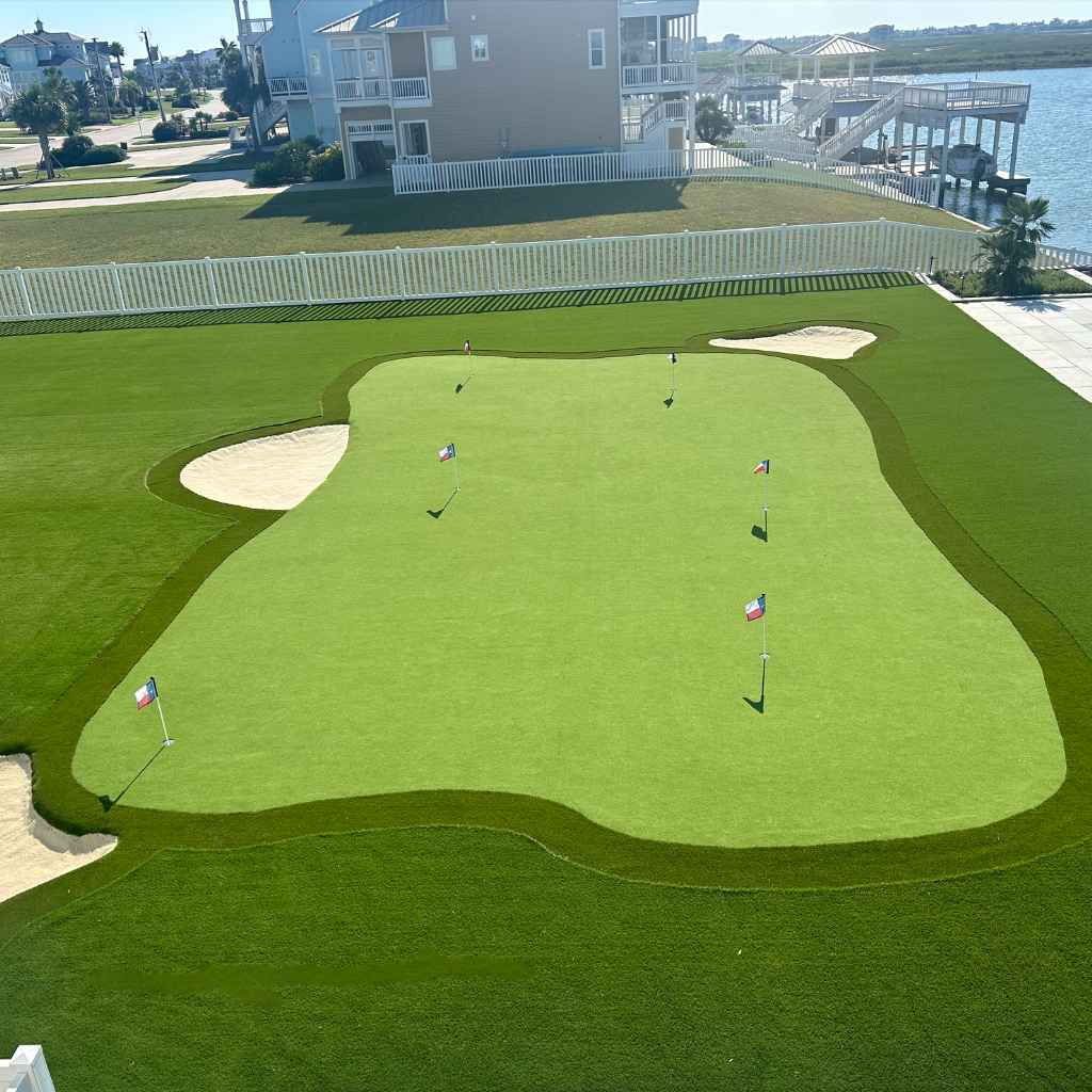 Luxury waterfront putting green with sand traps and Texas flags, installed by Sermons Turf Installs on Galveston Bay.