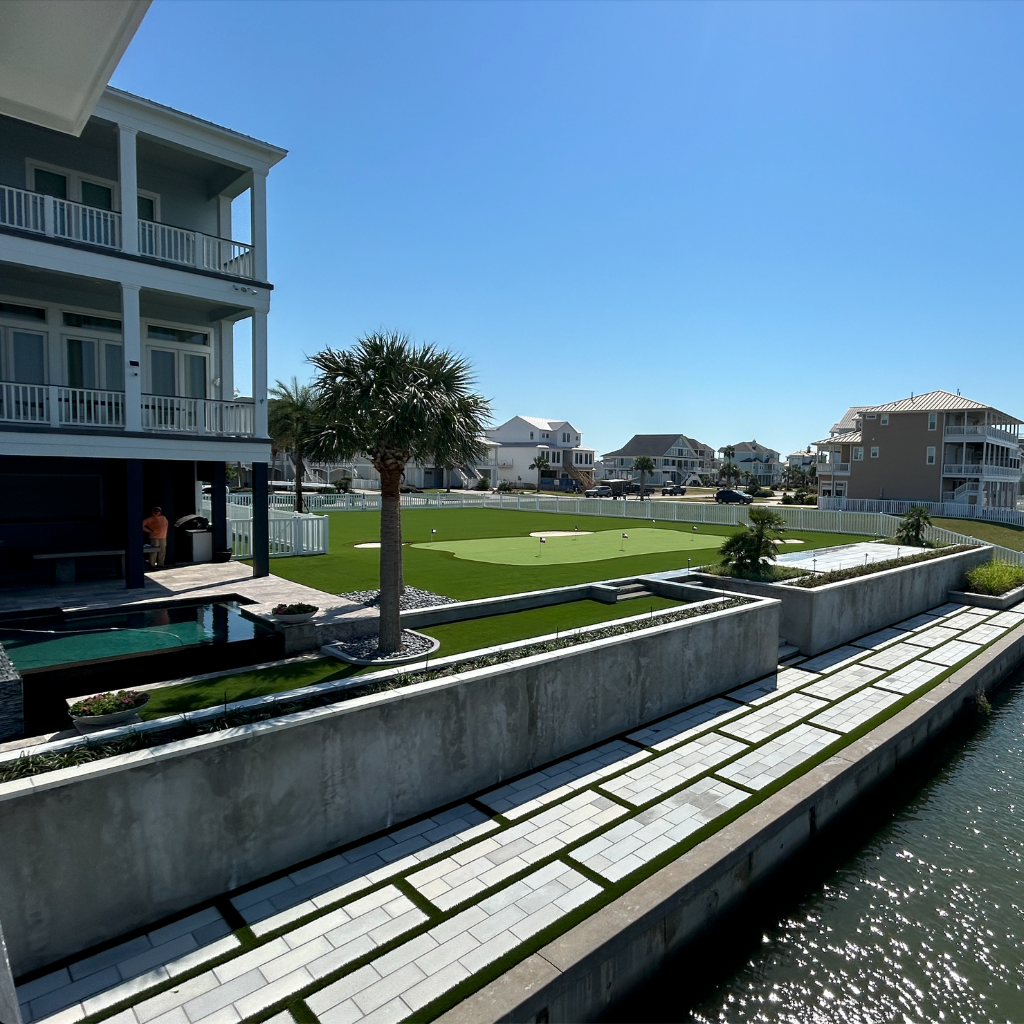 Luxury waterfront property on Galveston Bay with a custom putting green, paver work along the water, and a swimming pool.